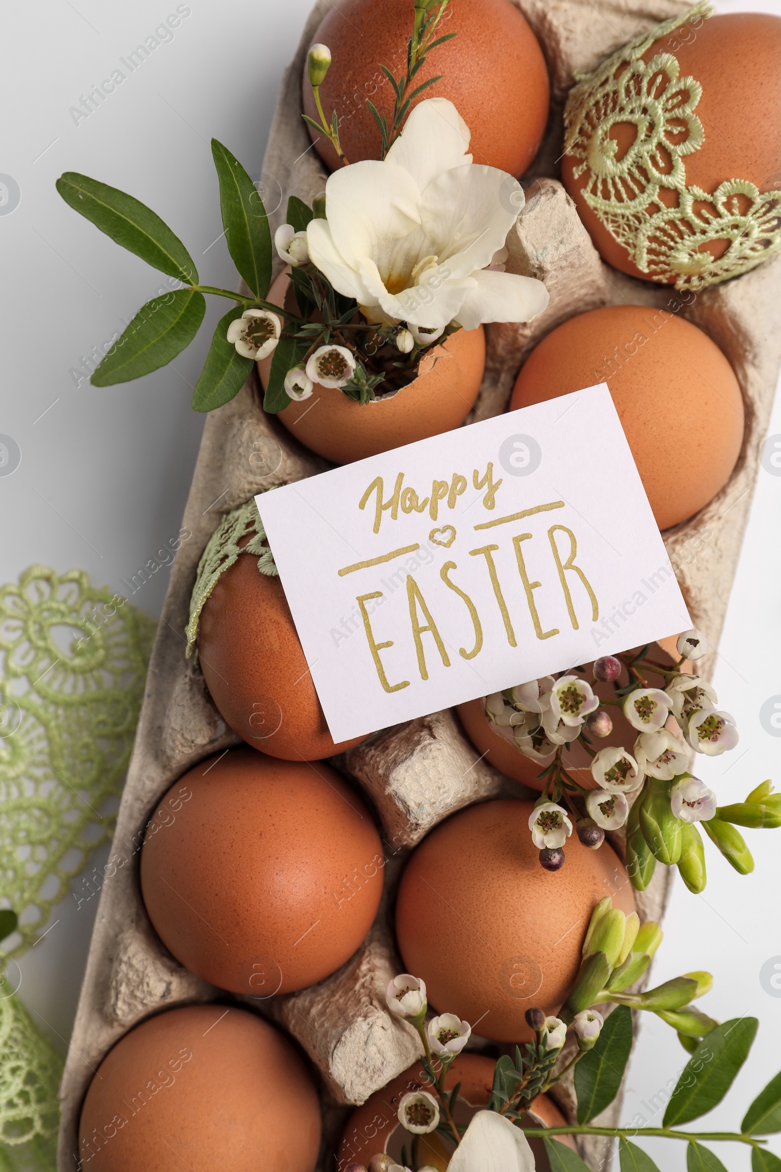 Photo of Card with words Happy Easter, eggs and green twigs on white background, flat lay