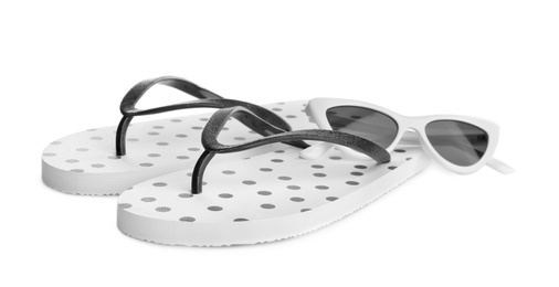 Stylish flip flops and sunglasses on white background