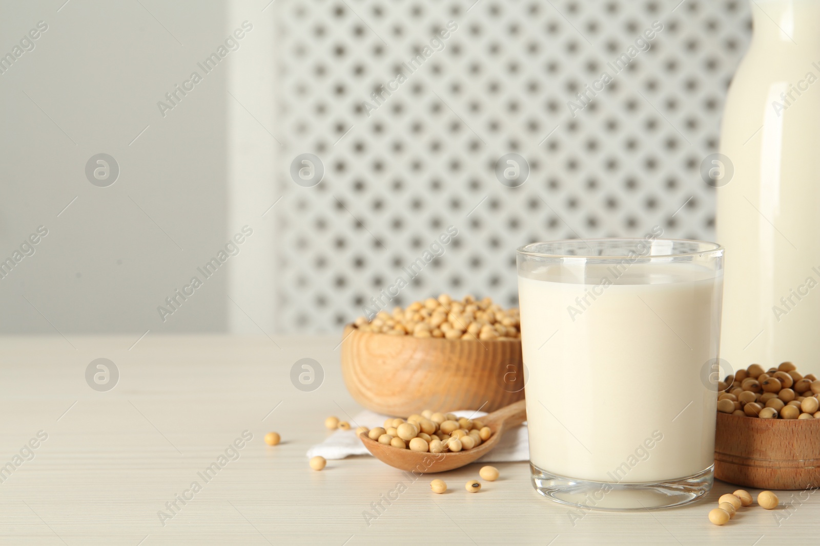 Photo of Soy milk and beans on wooden table, space for text