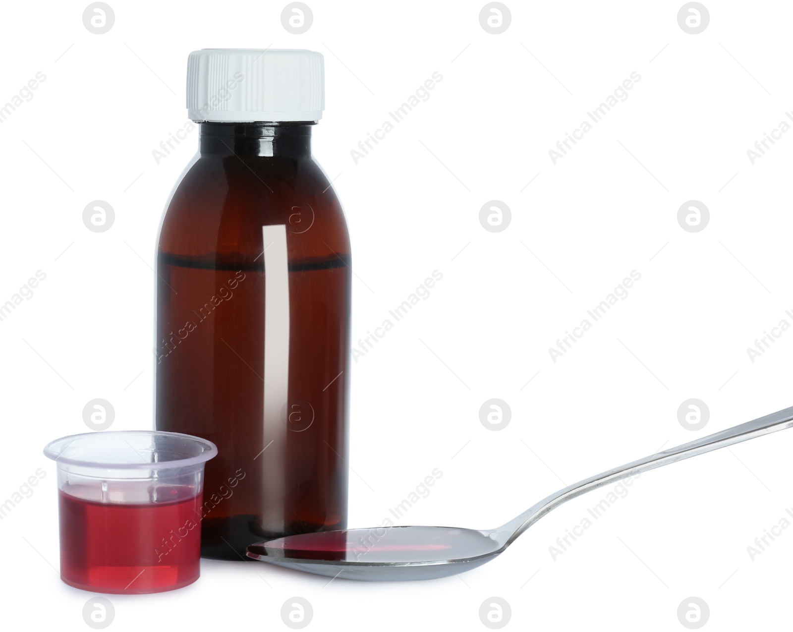 Photo of Bottle of cough syrup, spoon and measuring cup on white background