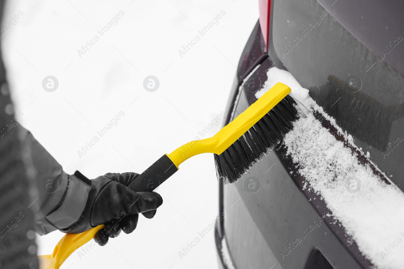 Photo of Man cleaning snow from car outdoors, closeup