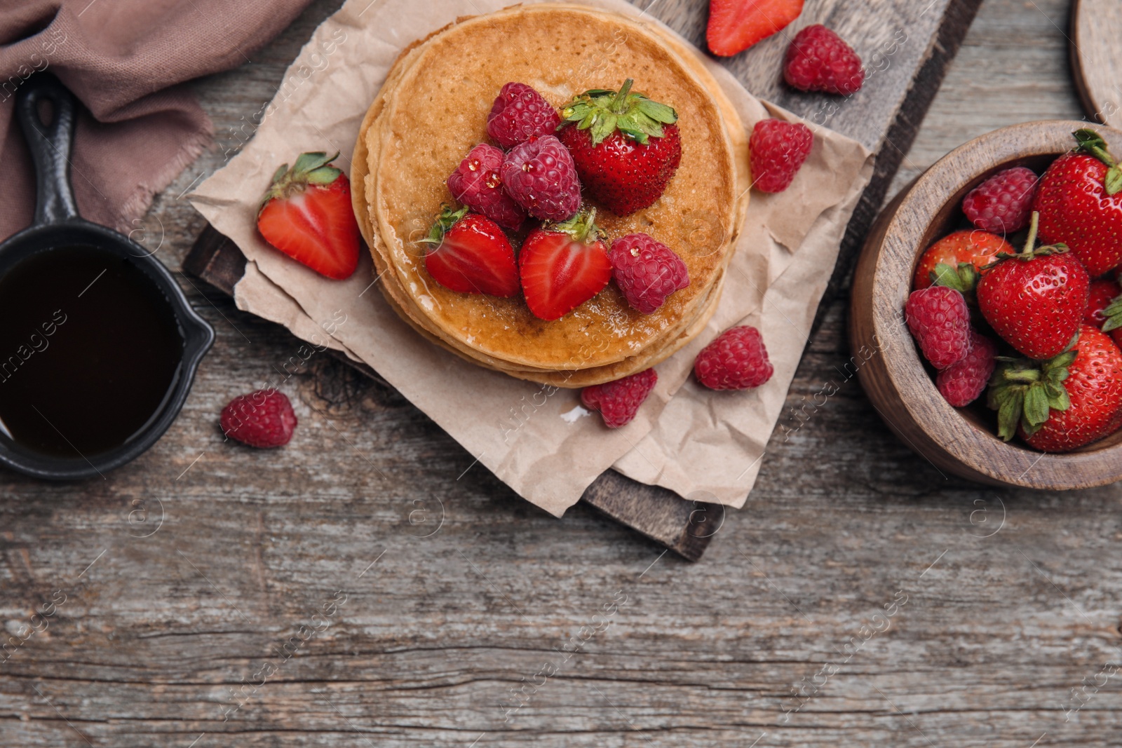 Photo of Tasty pancakes served with honey and berries on wooden table, flat lay. Space for text