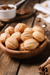 Photo of Homemade walnut shaped cookies with boiled condensed milk on wooden table, closeup