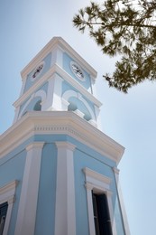 Photo of Beautiful tower with clock against blue sky, low angle view