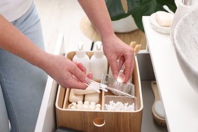 Photo of Bath accessories. Woman with cotton buds indoors, closeup