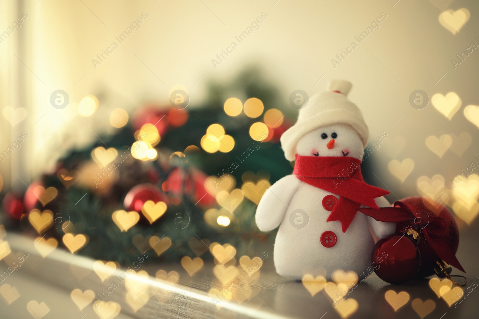 Image of Cute snowman and Christmas balls on table, bokeh effect. Space for text