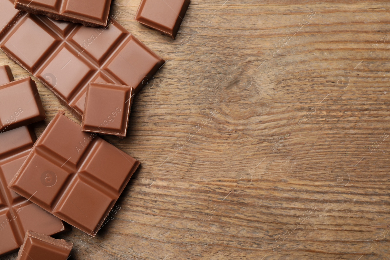 Photo of Delicious milk chocolate on wooden table, flat lay. Space for text