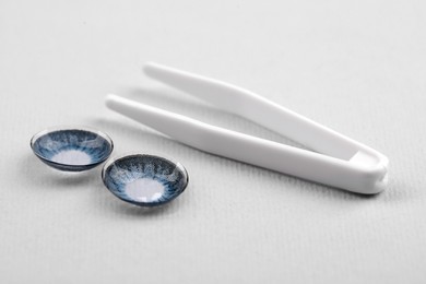 Photo of Blue contact lenses and tweezers on white background