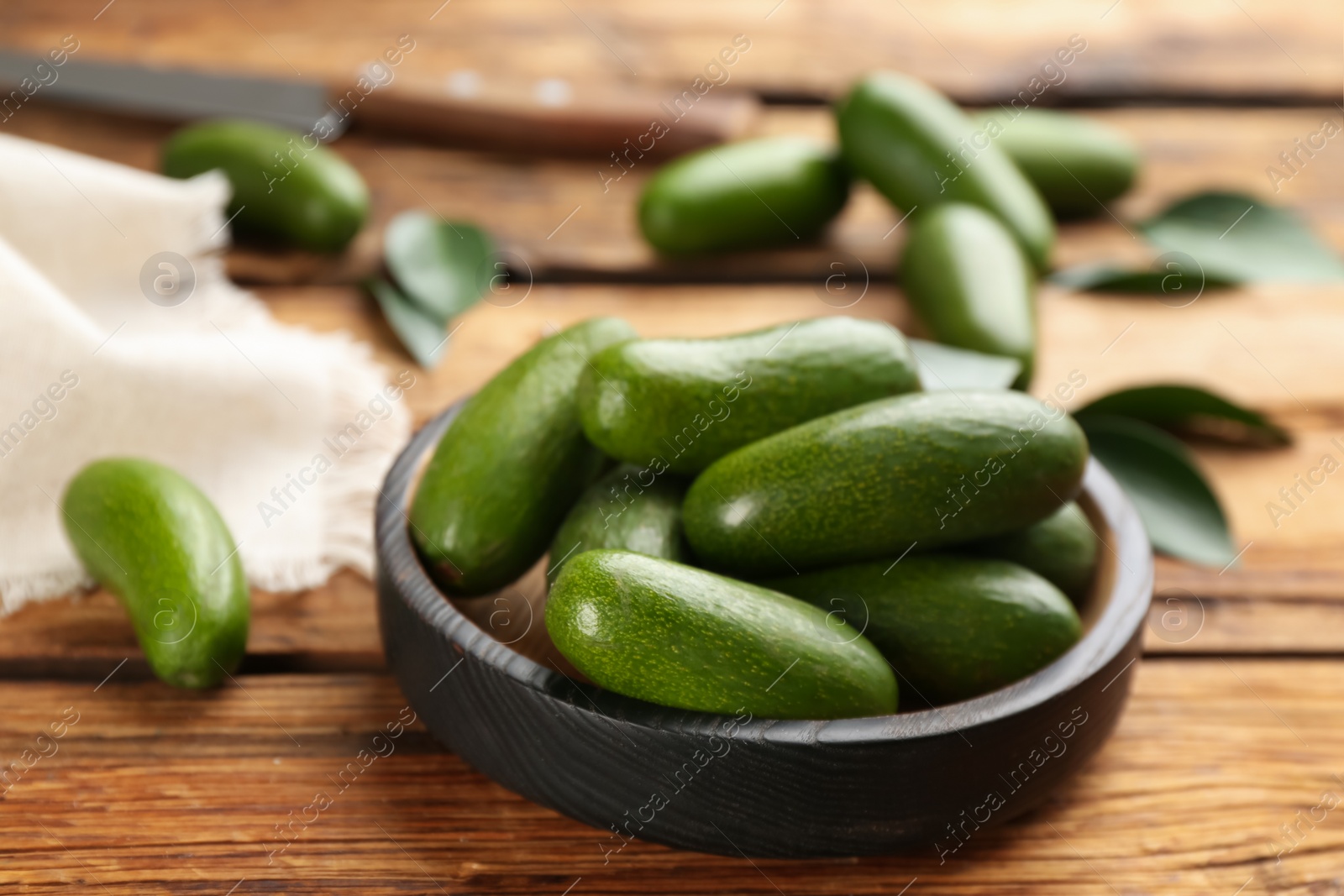 Photo of Fresh avocados with green leaves on wooden table, closeup