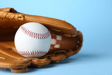 Photo of Catcher's mitt and baseball ball on light blue background, closeup with space for text. Sports game