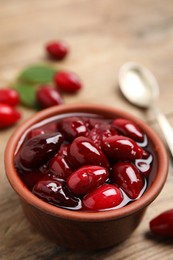 Delicious dogwood jam with berries in bowl on wooden table, closeup