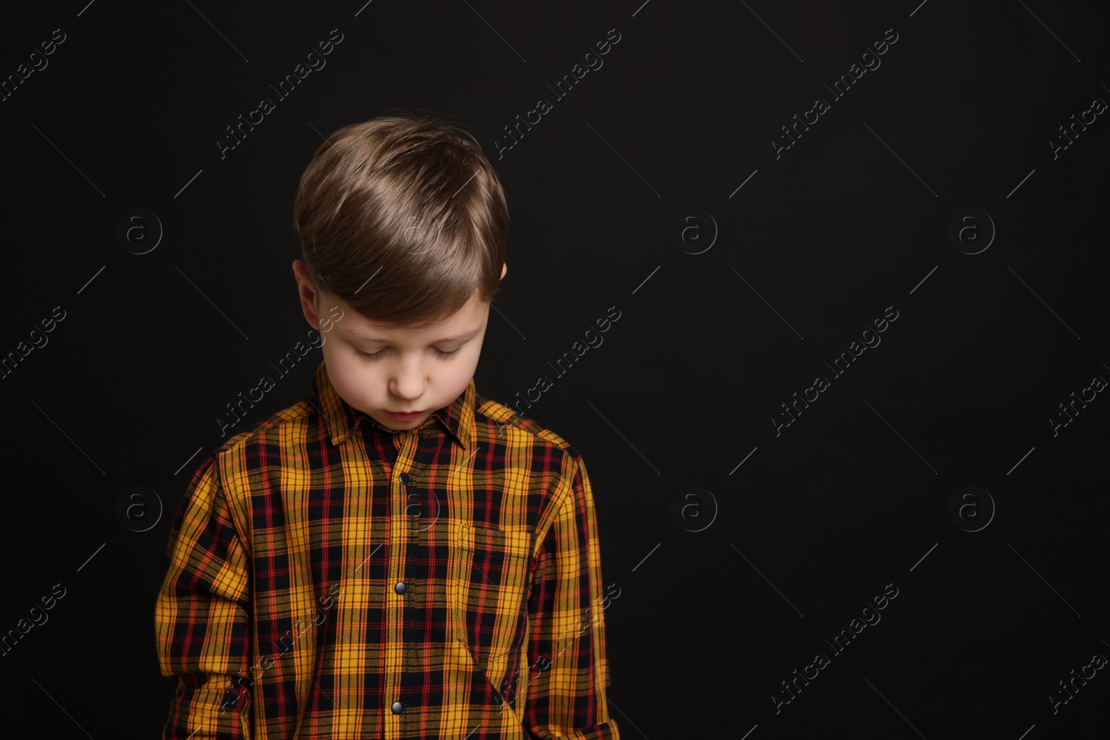 Photo of Upset boy on black background, space for text. Children's bullying