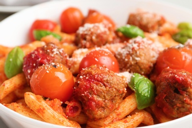 Delicious pasta with meatballs and tomato sauce on plate, closeup