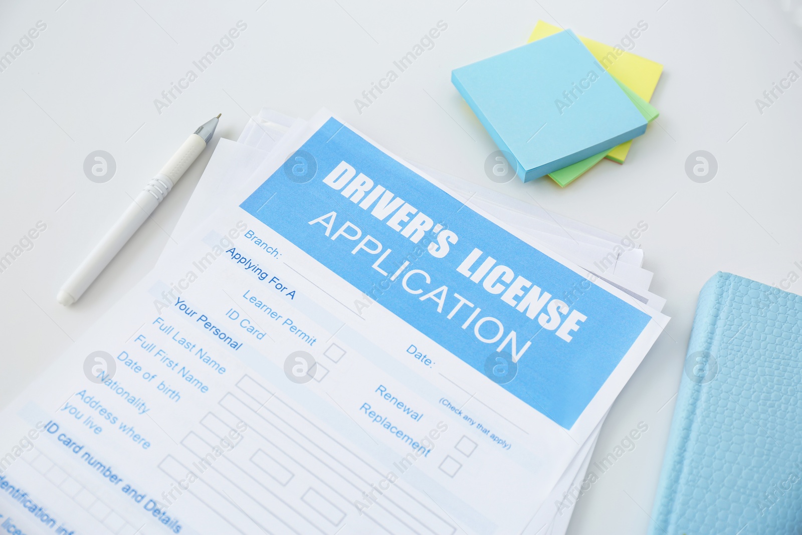 Photo of Driver's license application form and stationery on white table