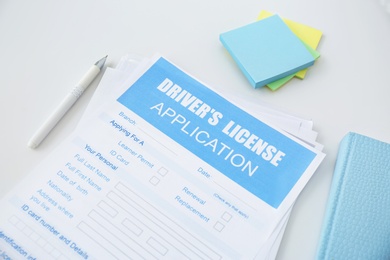 Driver's license application form and stationery on white table