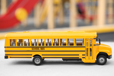 Yellow toy school bus against blurred background. Transport for students