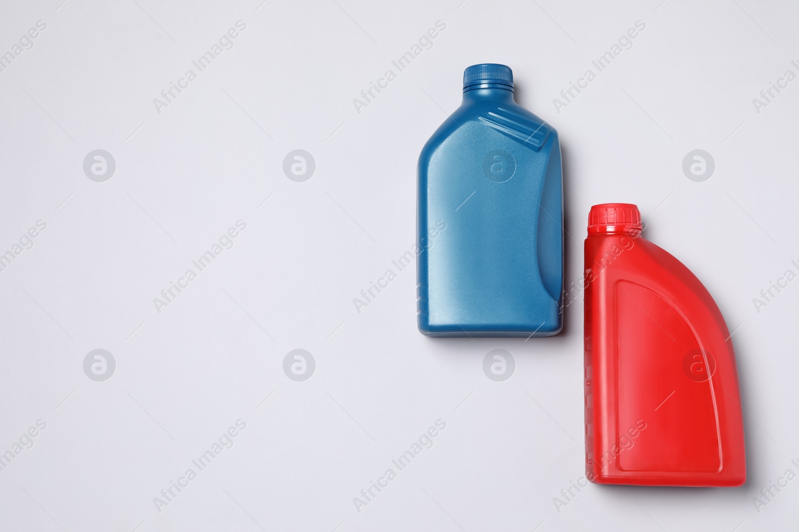 Photo of Motor oil in different canisters on light background, flat lay. Space for text