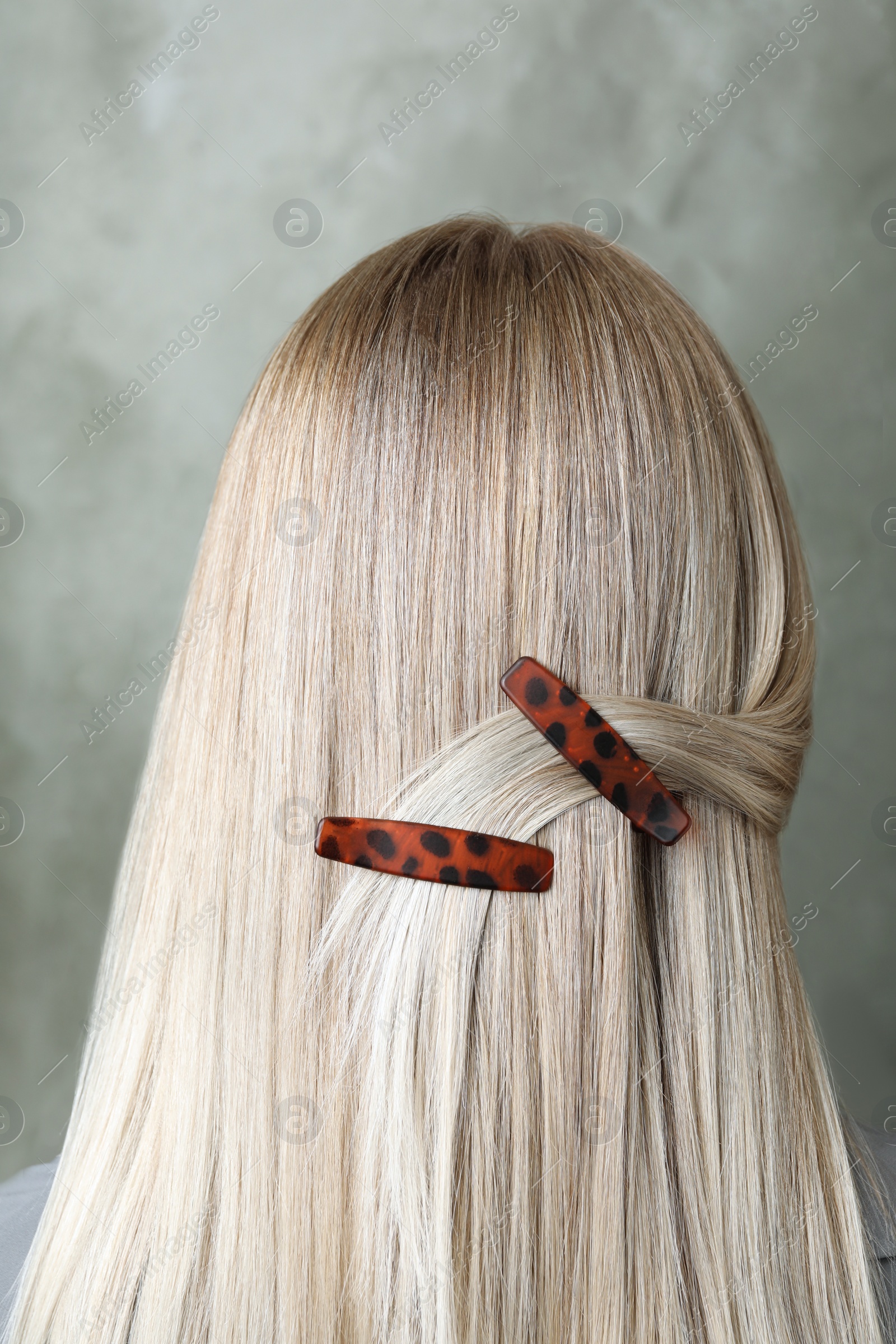 Photo of Young woman with beautiful hair clips on grey background, back view