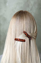 Young woman with beautiful hair clips on grey background, back view