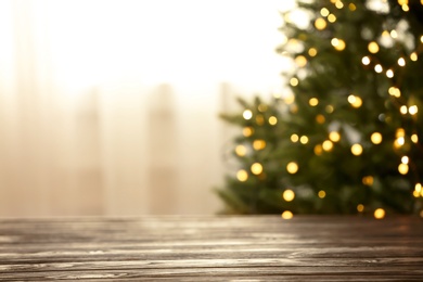 Photo of Empty table and blurred fir tree with yellow Christmas lights on background, bokeh effect. Space for design