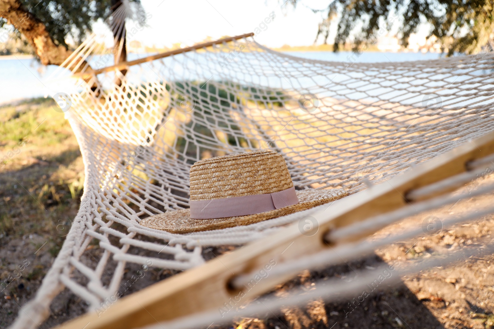 Photo of Hat in comfortable hammock on beach, closeup. Summer vacation