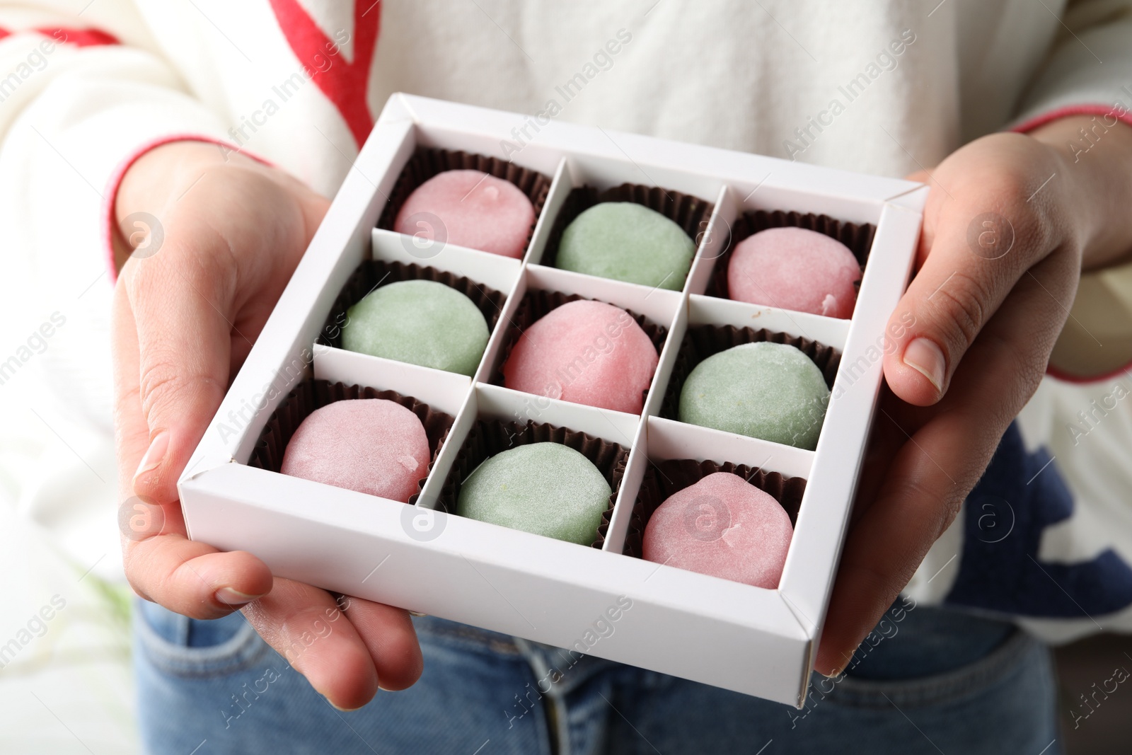 Photo of Woman holding box with different delicious mochi, closeup