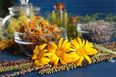 Photo of Bowl and many different herbs on blue wooden table, closeup