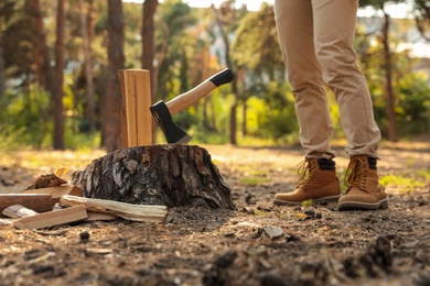 Man chopping firewood with axe in forest, closeup