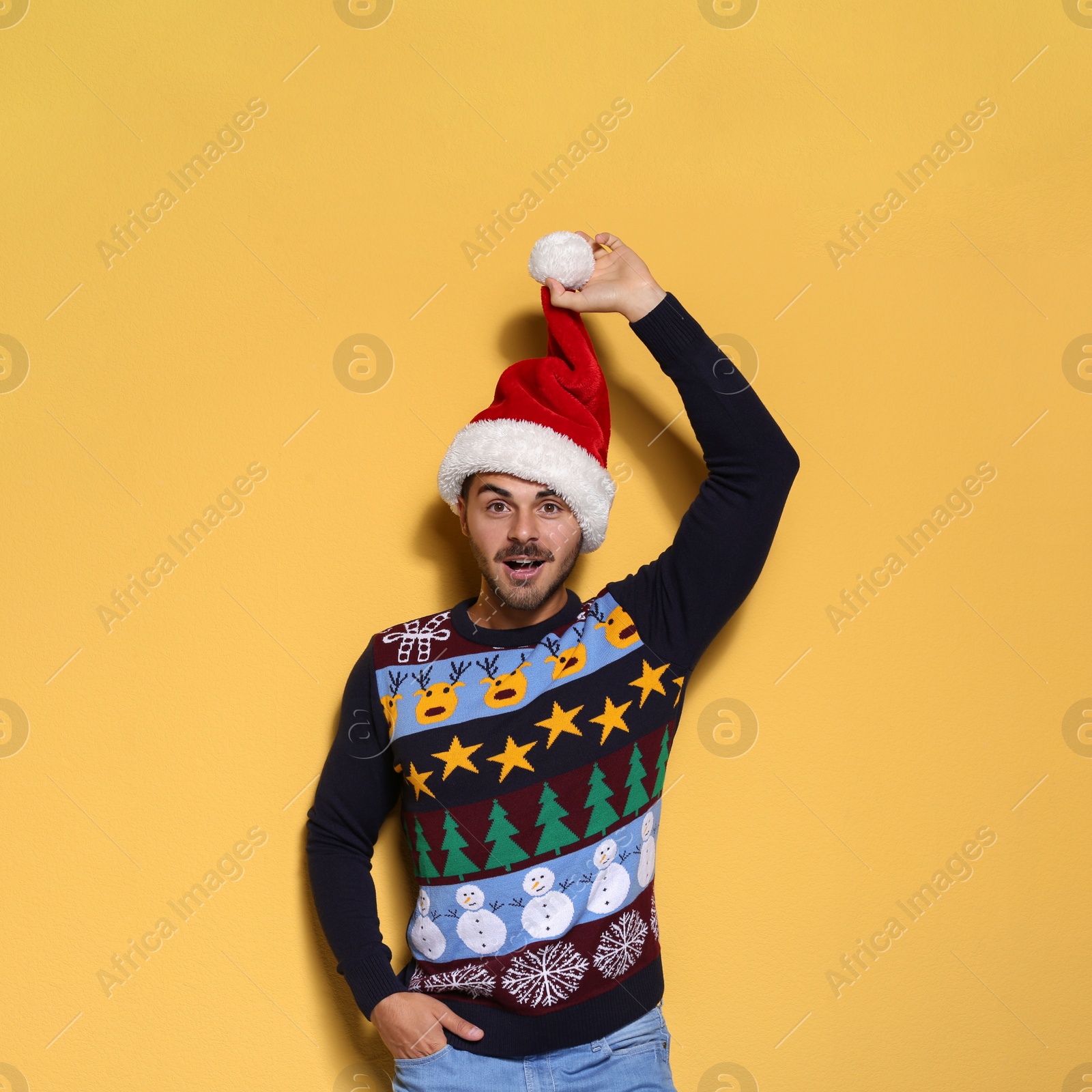 Photo of Young man in Christmas sweater and hat on color background