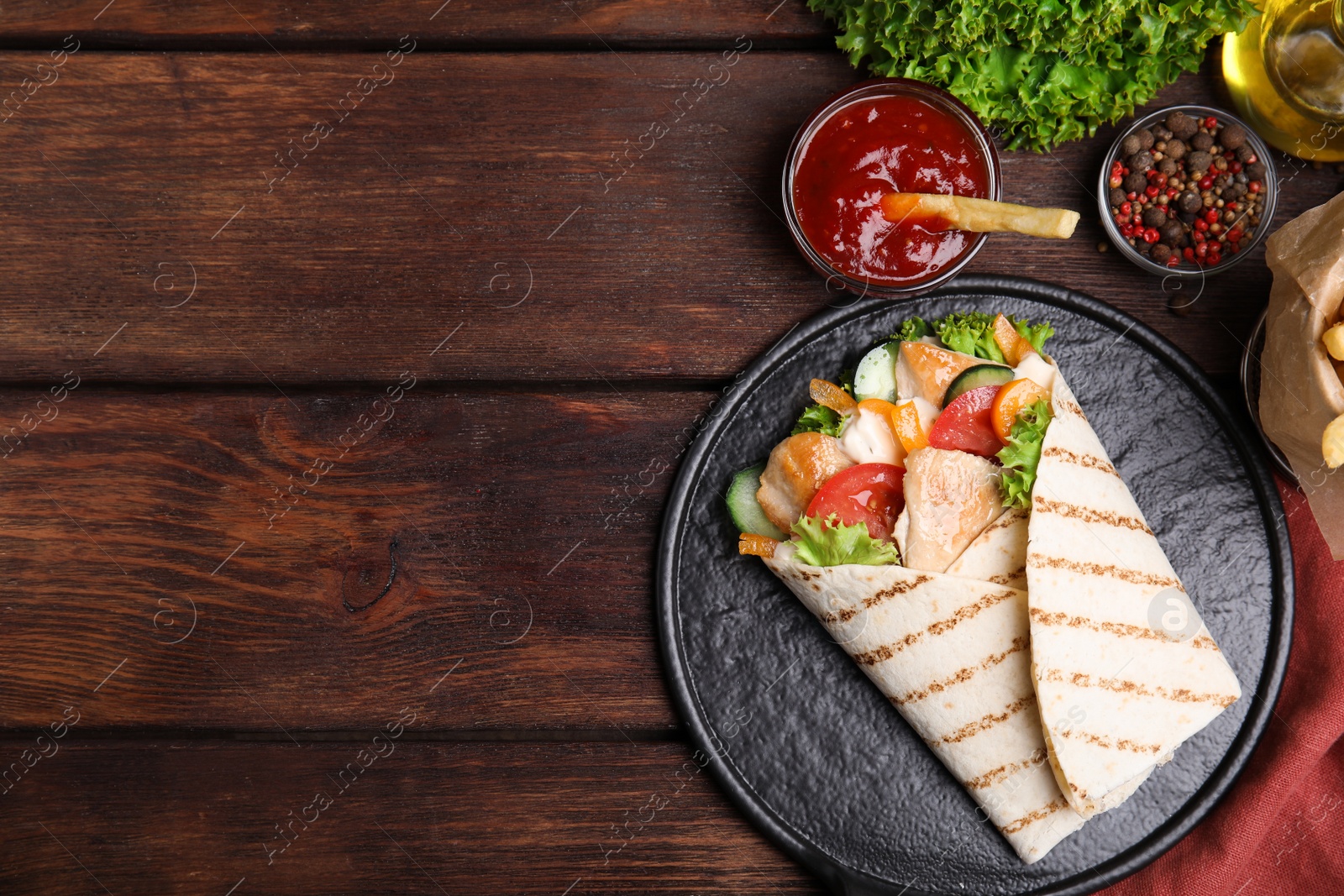 Photo of Delicious shawarma with chicken meat and vegetables  served on wooden table, flat lay. Space for text