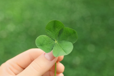 Photo of Woman holding four-leaf clover outdoors, closeup