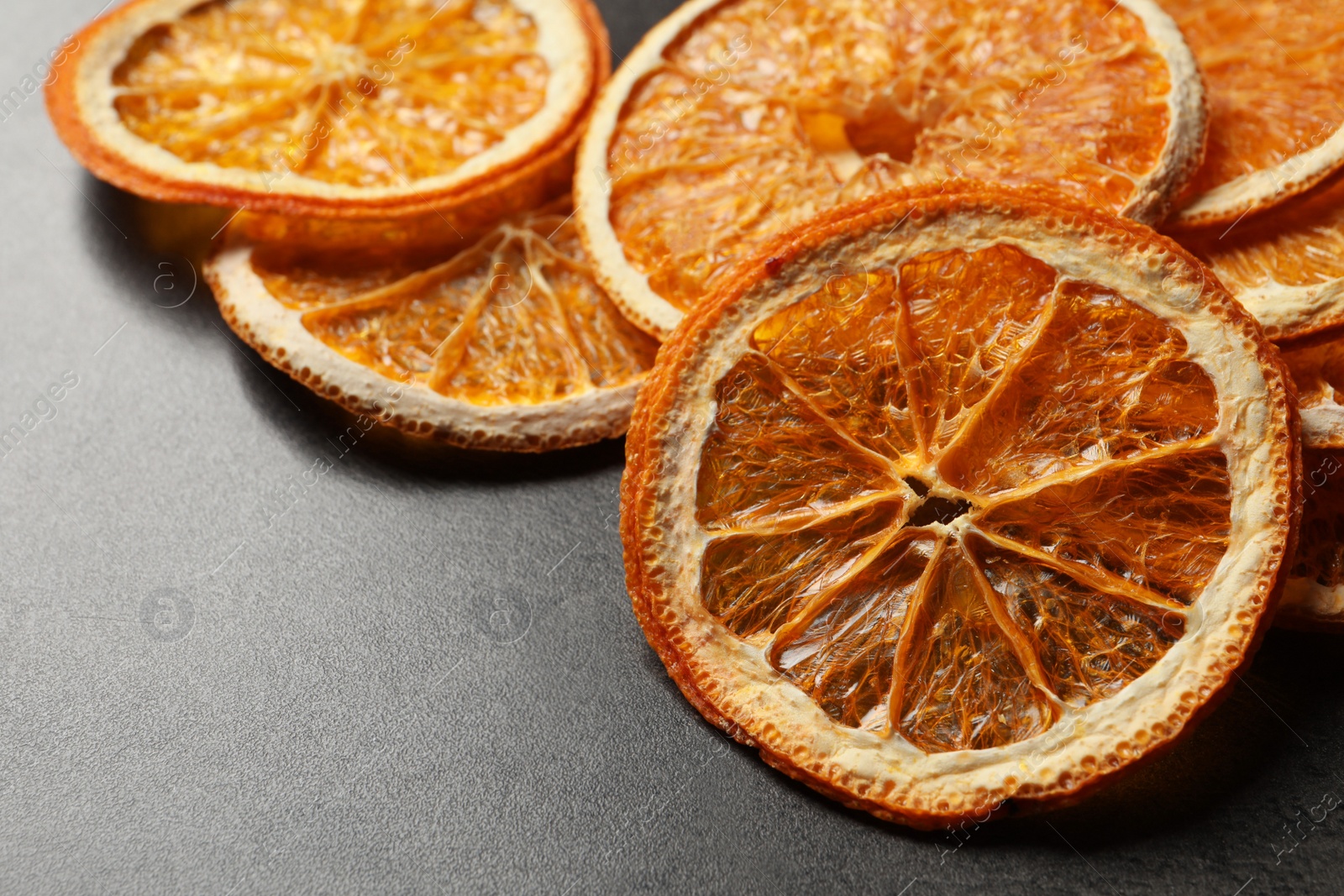 Photo of Dry orange slices on black table, closeup. Space for text