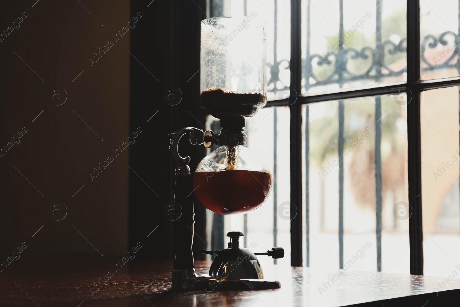 Photo of Vacuum coffee maker on wooden table in cafe