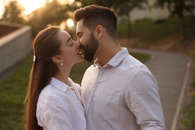Photo of Lovely couple kissing and dancing together outdoors at sunset