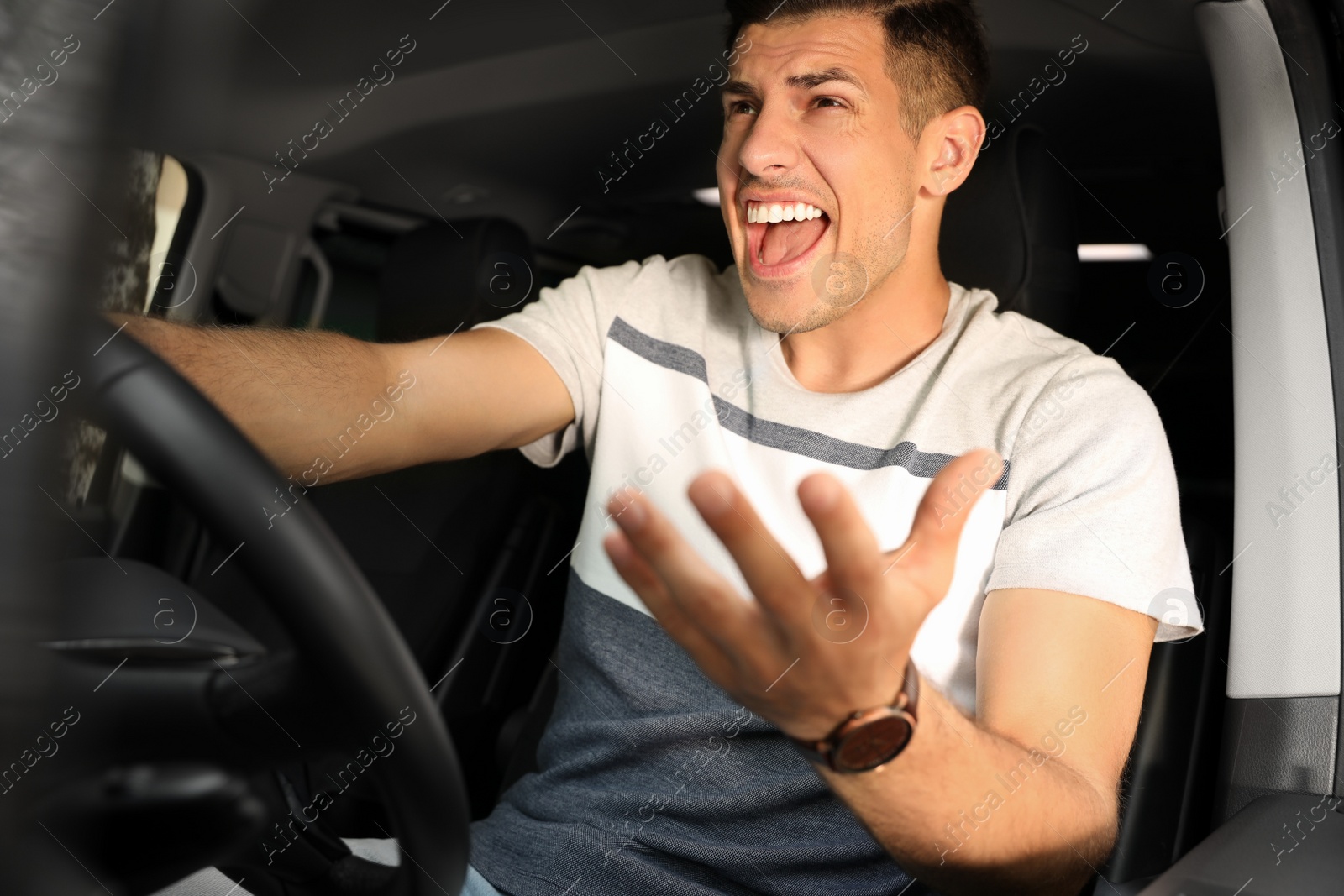 Photo of Emotional man yelling in car. Aggressive driving behavior