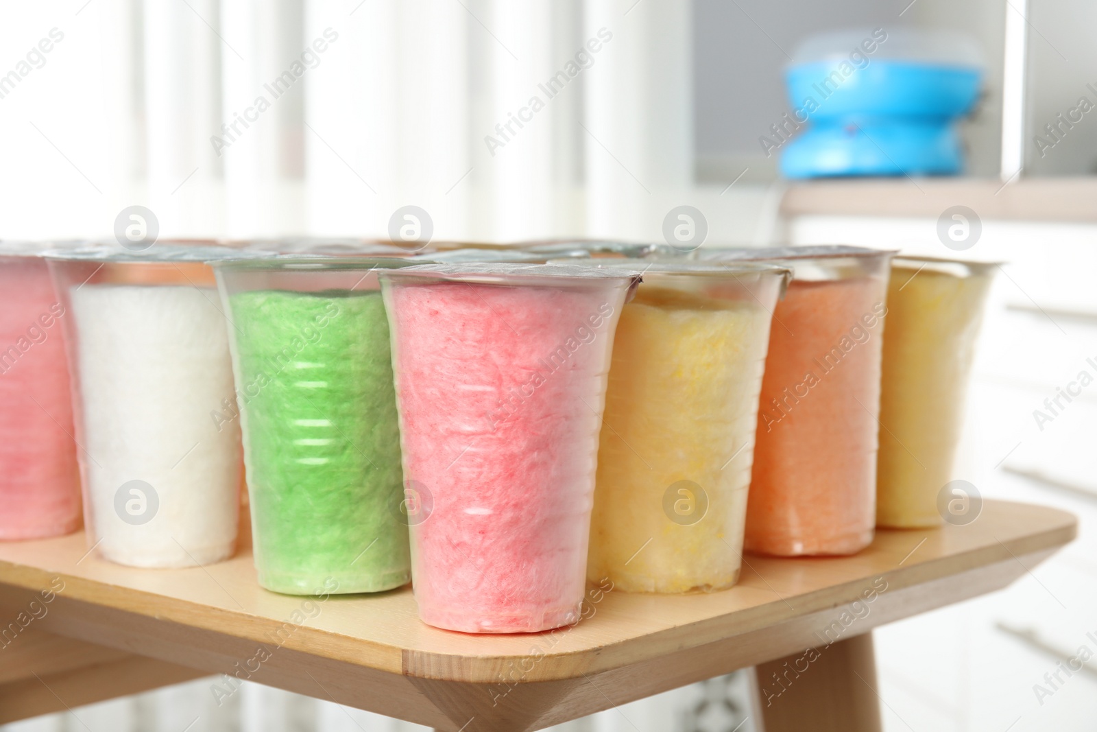 Photo of Plastic cups with cotton candy on table against blurred background