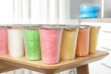 Plastic cups with cotton candy on table against blurred background
