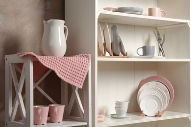 Stylish storage stand with different ceramic dishware at home