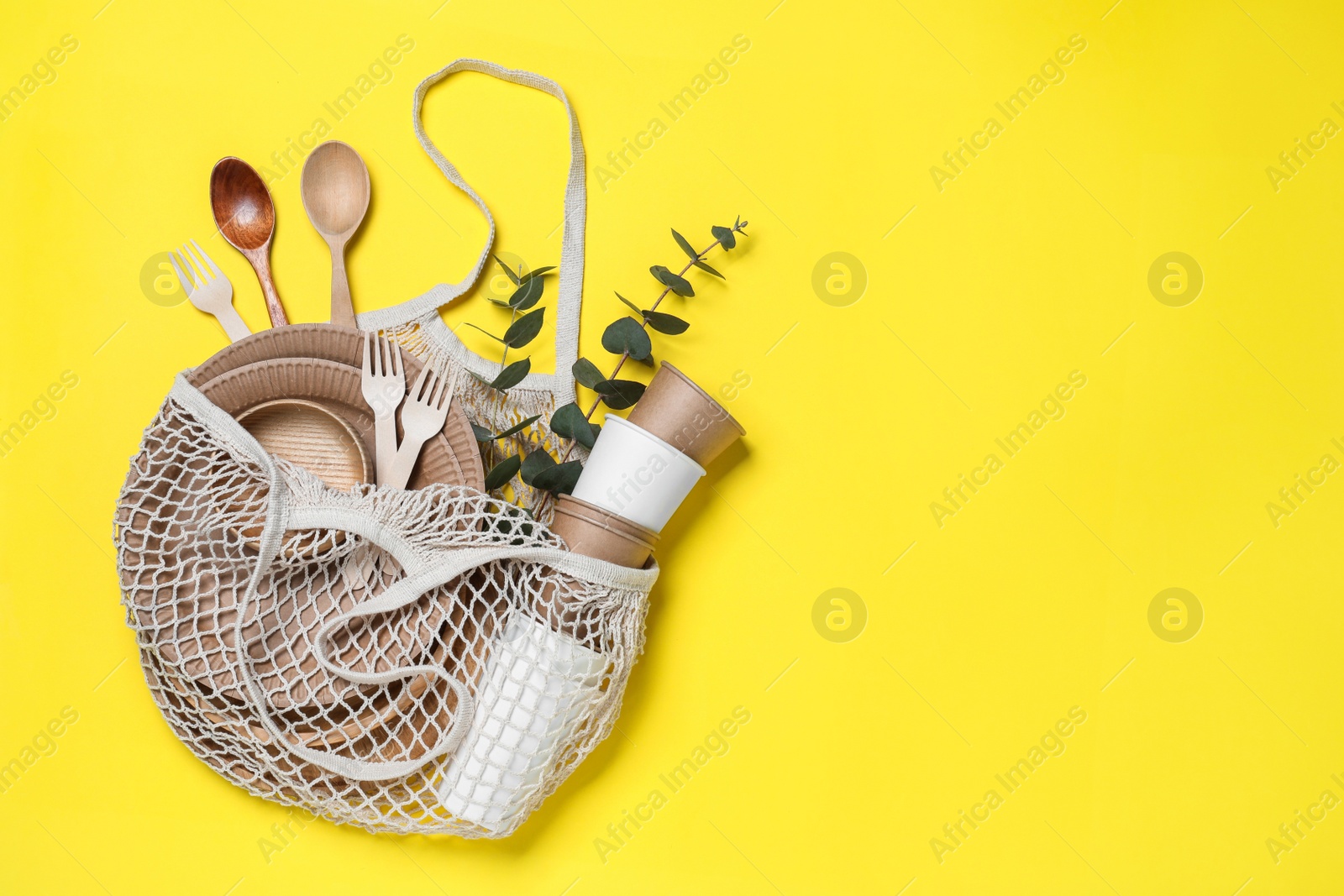 Photo of Net bag with different eco items on yellow background, top view and space for text. Recycling concept