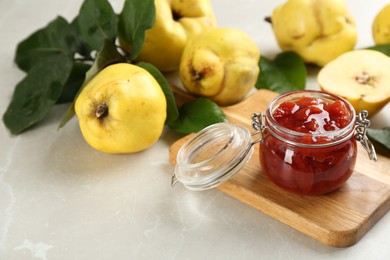 Photo of Delicious quince jam and fruits on light grey marble table