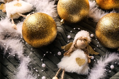 Composition with beautiful golden Christmas baubles on green knitted plaid