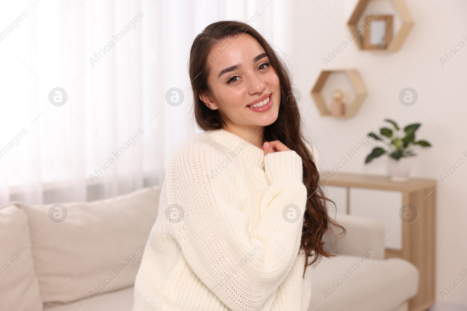 Photo of Beautiful young woman in stylish warm sweater at home