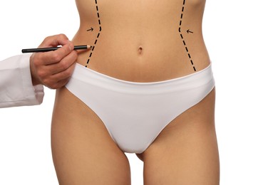 Woman preparing for cosmetic surgery, white background. Doctor drawing markings on her abdomen, closeup