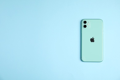 Photo of MYKOLAIV, UKRAINE - JULY 10, 2020: New modern Iphone 11 Green on light blue background, top view. Space for text