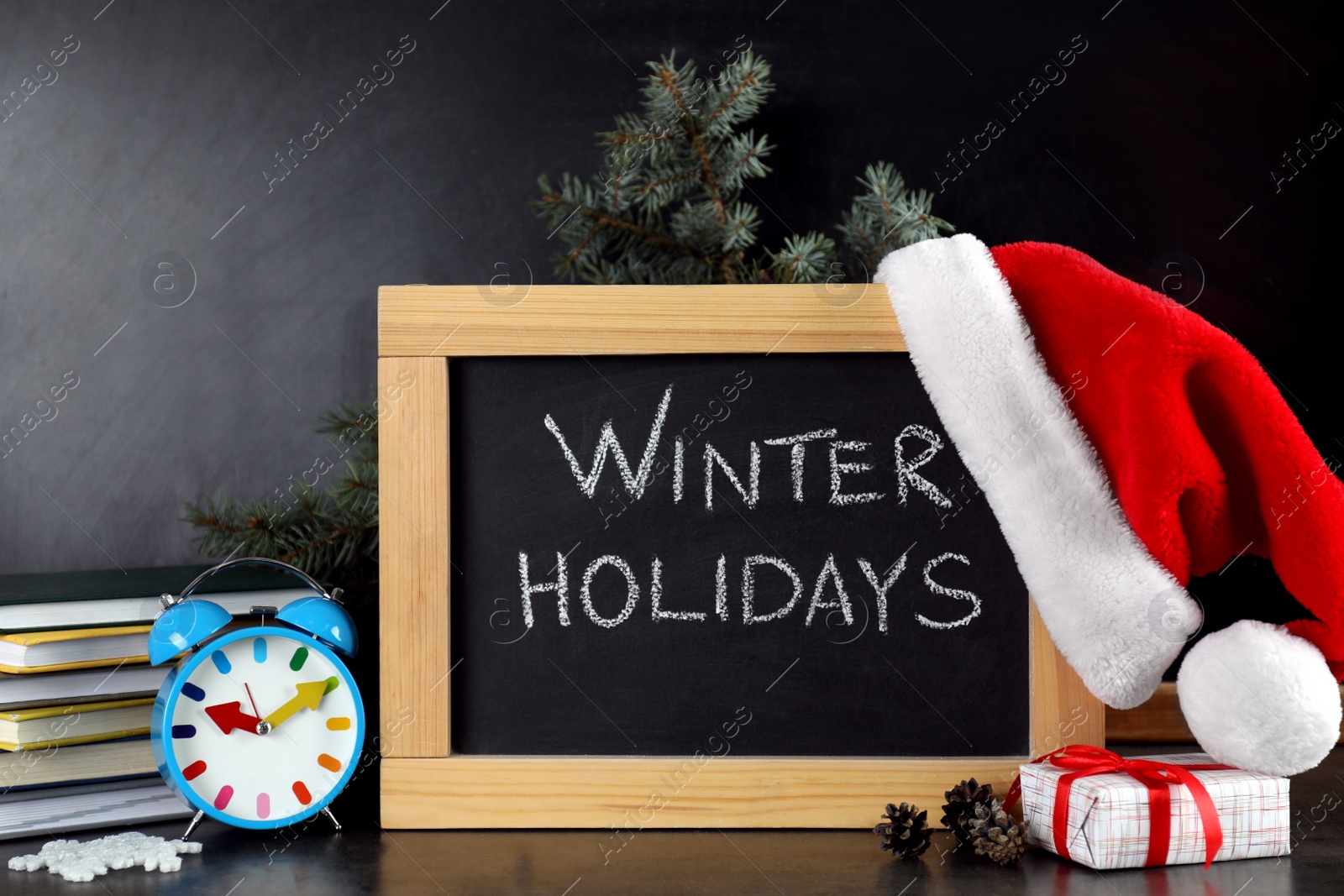 Photo of Blackboard with text Winter Holidays and Christmas decor on table