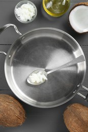 Photo of Flat lay composition with frying pan and organic coconut cooking oil on grey wooden table