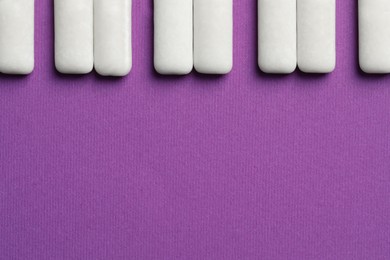 Photo of Tasty white bubble gums on purple background, flat lay. Space for text