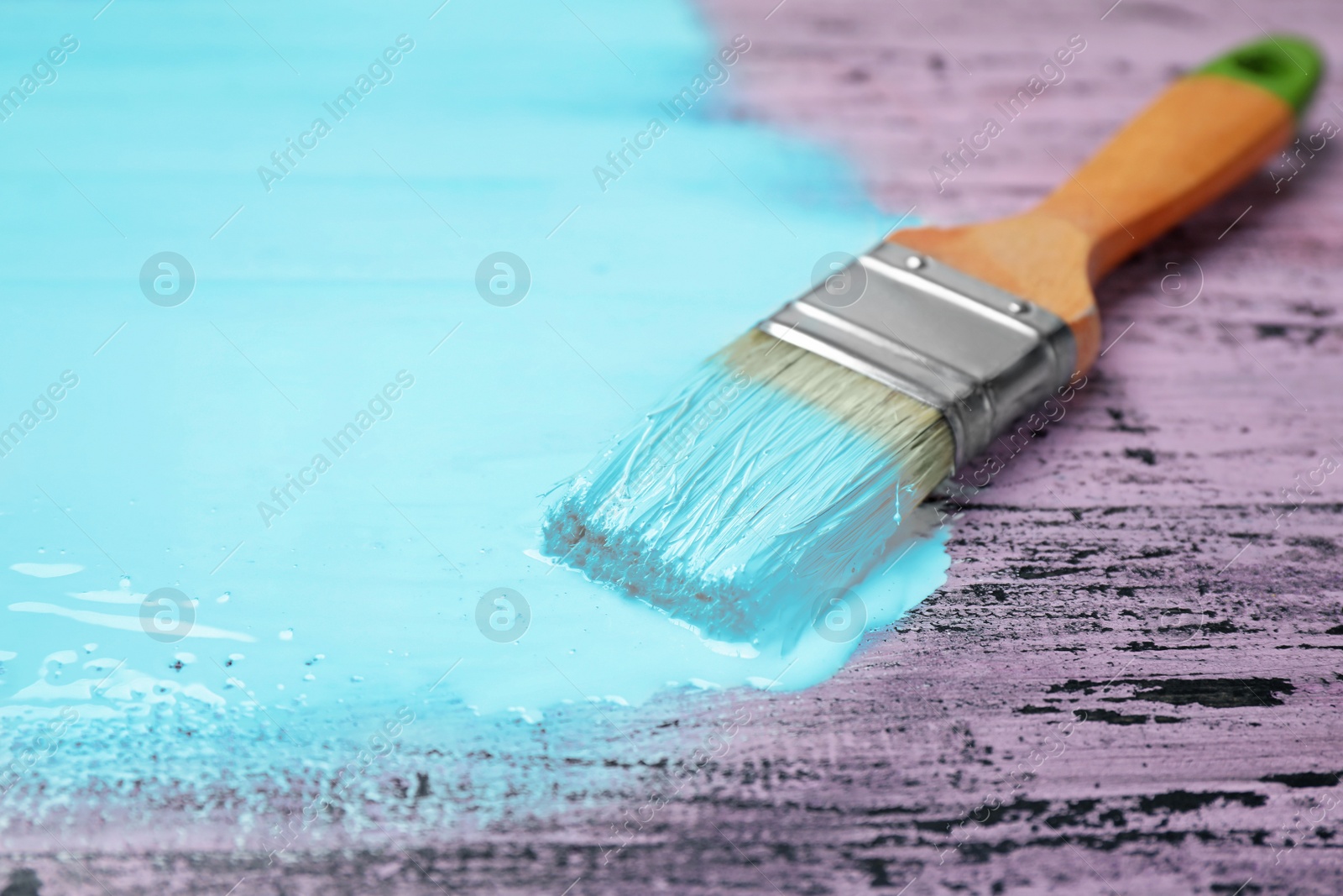 Photo of Brush with blue paint on pink wooden background, space for text