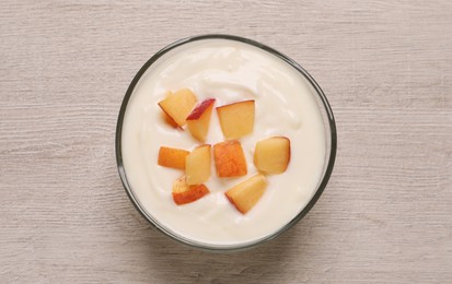 Photo of Delicious yogurt with fresh peach on light wooden table, top view