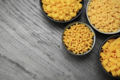 Photo of Different types of pasta on grey table, flat lay. Space for text
